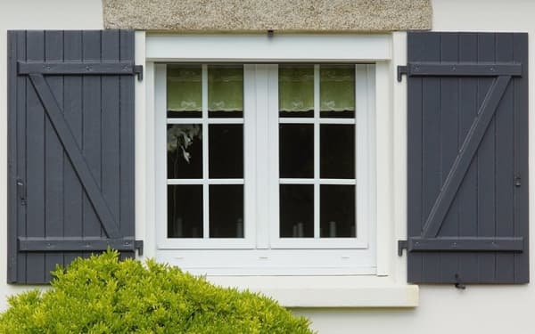 Weiße Fenster mit dunkelgrauen Fensterläden an einer Hausfassade
