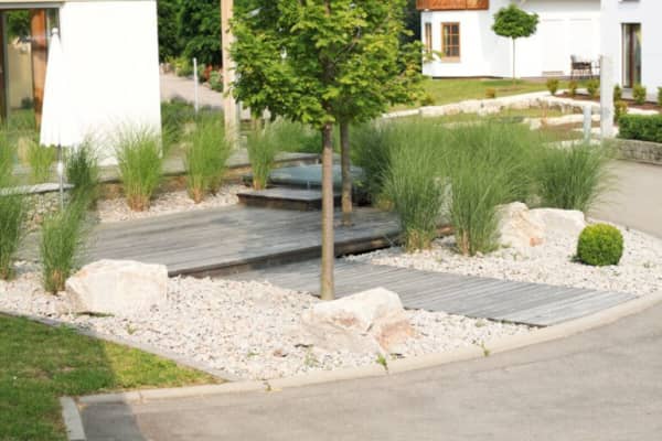 Moderner Garten mit Holzplatten, Steinen und Sträuchern