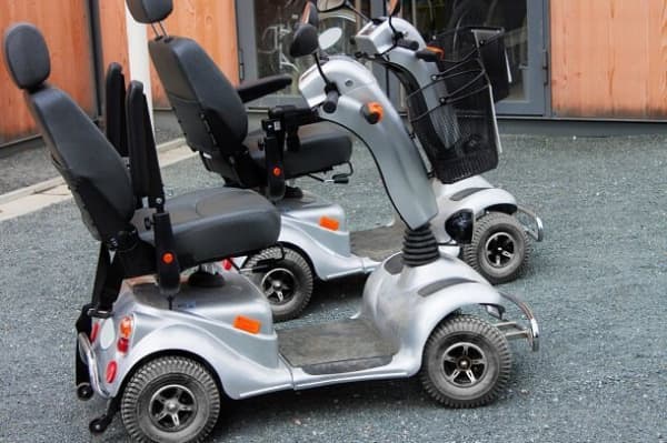 Zwei Elektromobile mit Taschenkorb und hochgeklappten Armstützen.