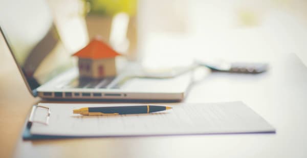 Laptop mit Haus und Klemmbrett auf Schreibtisch