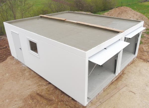 Weiße Doppelgarage aus Beton auf einer Baustelle.