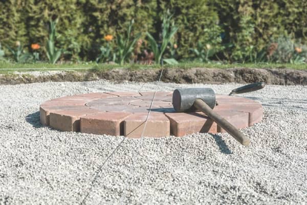 Auf der Terrasse werden Pflastersteine von einem Handwerker verlegt.