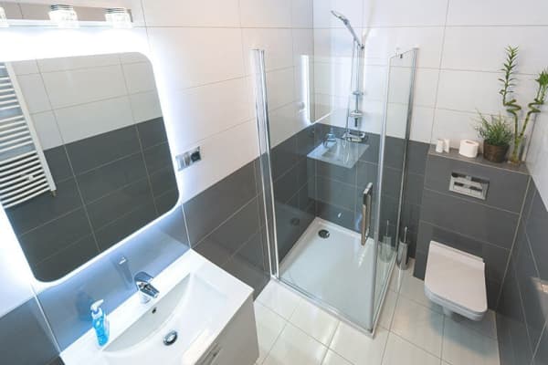 Ein beleuchteter Spiegel  hängt über dem Waschbecken in einem modernen Badezimmer, das mit Aroundhome geplant wurde