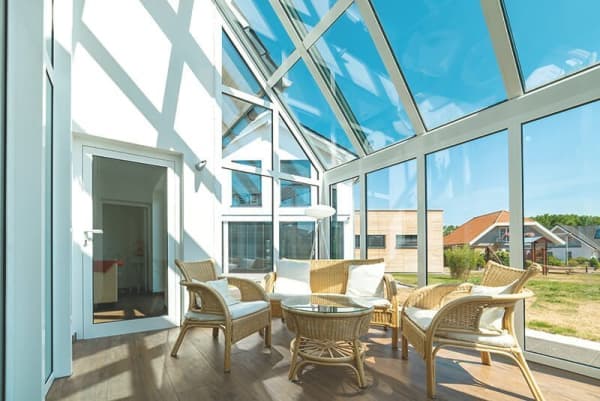 Moderner Wintergarten mit Glasdach und Rattanmöbeln
