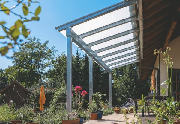 Terrassenüberdachung aus Metall vor sommerlichem Garten