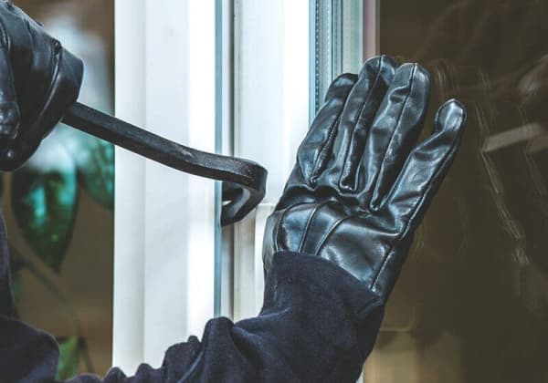 Einbruch mit Brecheisen an Fenster – Nahaufnahme mit Handschuhen