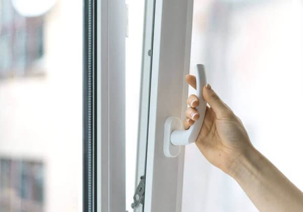 Hand öffnet weißes Kunststofffenster – Nahaufnahme des Fenstergriffs