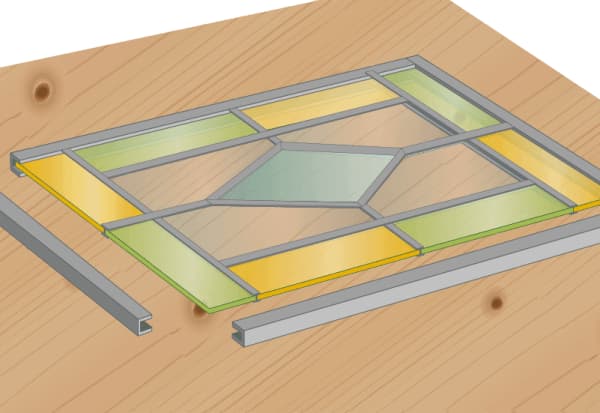 Buntglas-Fensterrahmen auf Holztisch – Glasstücke und Metallprofile