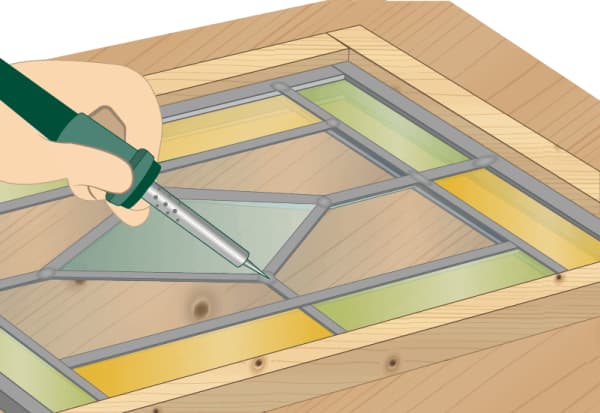 Hand lötet Bleiverbindungen eines Buntglasfensters auf Holztisch