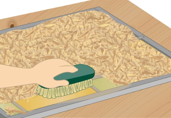 Hand entfernt Sägemehl von Bleiglasfenster nach Kittreinigung