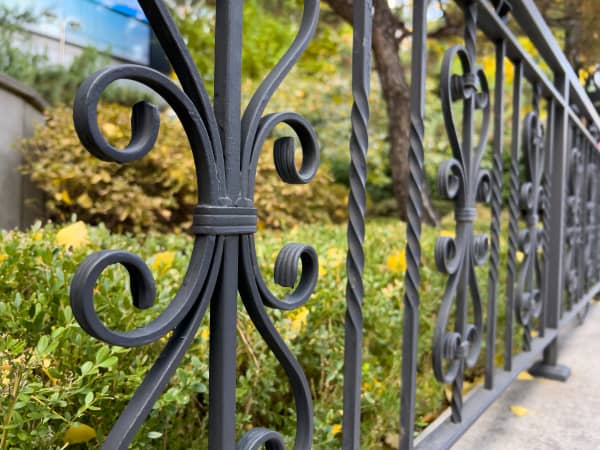 Nahaufnahme eines Teils eines schwarzen Schmuckzauns als Begrenzung zu einer Straße