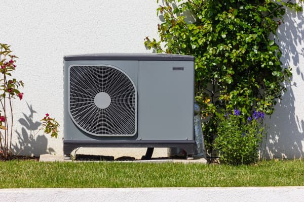 Wärmepumpe im Garten vor einem Eigenheim