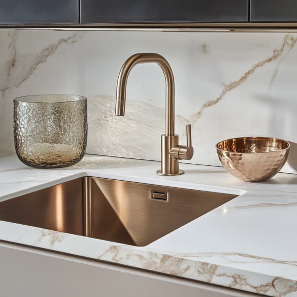 elegante Küchenspüle mit einem gebürsteten bronzenen Wasserhahn und passender Spüle