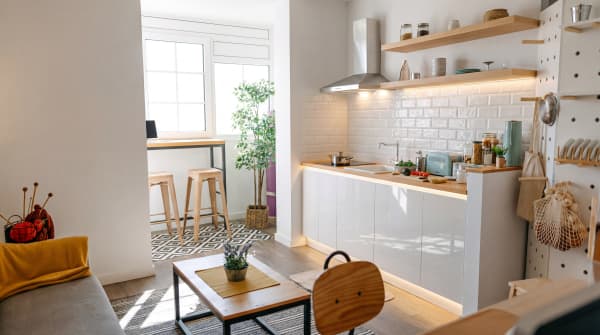 Kleine Wohnküche im modernen Stil mit weißen Unterschränken, Holz-Arbeitsplatte, schwarzer Tafelrückwand, Oberschränken mit Drahtglas und Grünpflanzen.