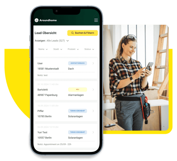 Im Vordergrund steht ein Mobiltelefon mit dem Partner Cockpit von Aroundhome, im Hintergrund bedient eine freundliche Handwerkerin das Cockpit auf dem Handy.