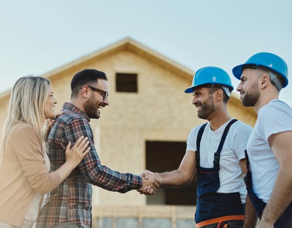Bild von zufriedenen Hauseigentümern und Handwerkern, die sich die Hände schütteln.