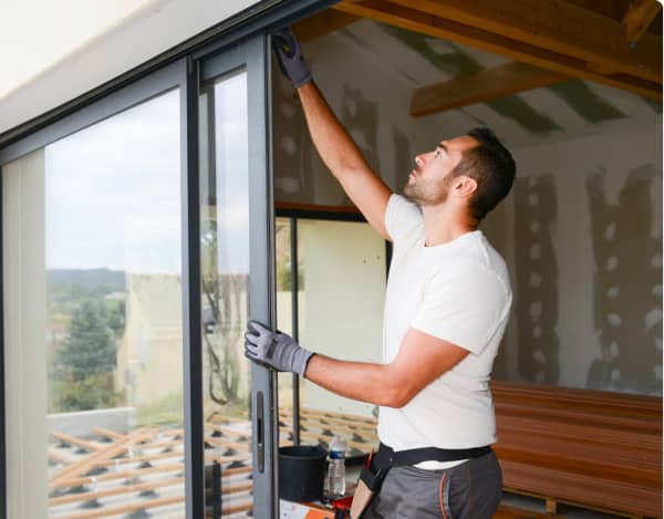 Handwerker montiert große Schiebetür aus Glas in Rohbau
