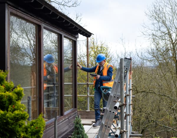 Bild von zufriedenen Hauseigentümern und Handwerkern, die sich die Hände schütteln.