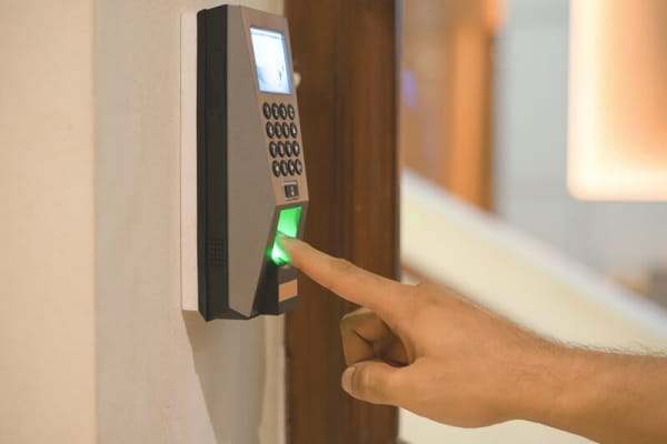 Nahaufnahme einer Hand, die einen Finger unter den Fingerabdruck-Sensor des Bedienmoduls einer Alarmanlage hält