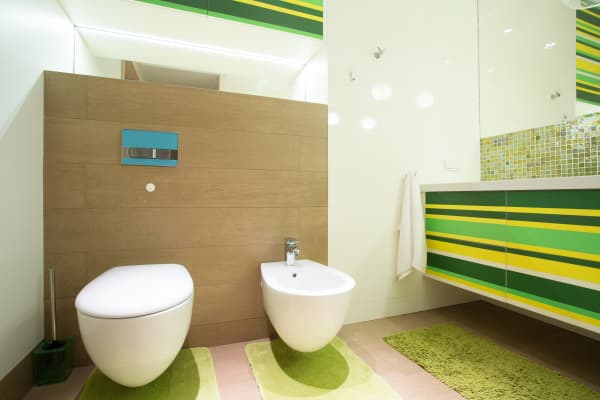 Modernes Bad mit wandhängender Toilette, Bidet und großem Waschtisch mit Unterbauschrank in grün und gelb