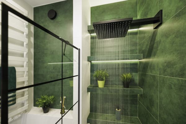 Beleuchtete Regendusche in einem Badezimmer mit waldgrünen Wandfliesen und schwarzen Armaturen