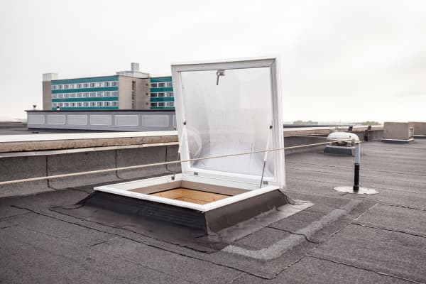 Offenes Dachlukenfenster auf einem Flachdach eines Mehrfamilienhauses