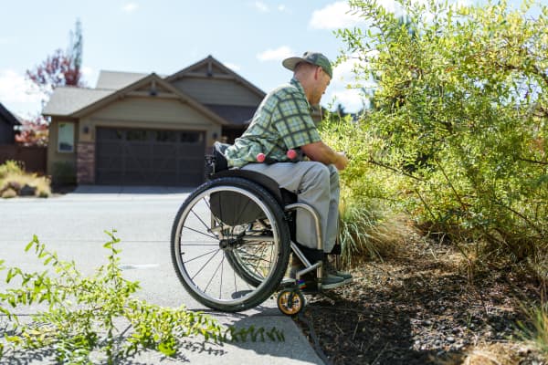 Mann im Rollstuhl arbeitet am Beet