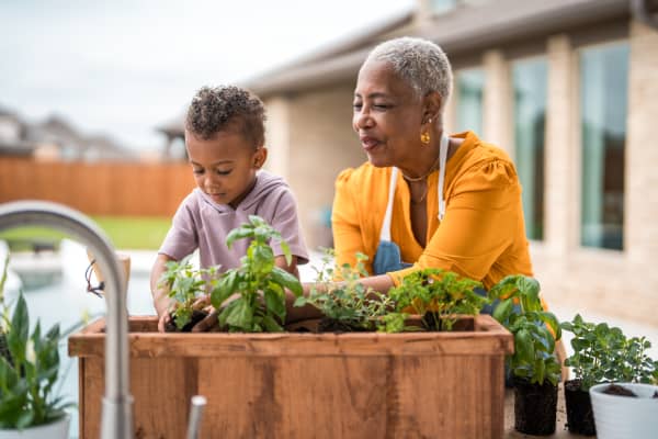 Frau mit Kind arbeitet am Kräuterbeet