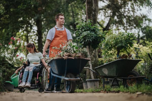 Junger Mann mit Downsyndrom schiebt Schubkarre