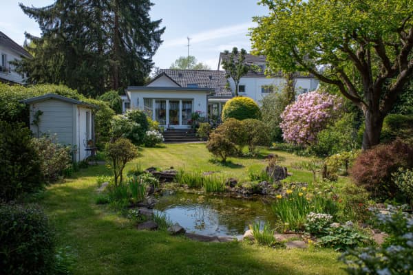 Ein großer Garten mit Teich und einem Haus im Hintergrund.