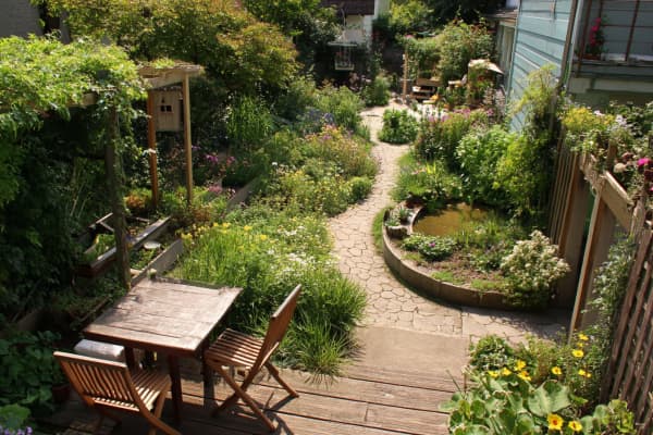 Kleiner Garten naturnahe gestaltet mit Terrasse, Weg und Beeten.