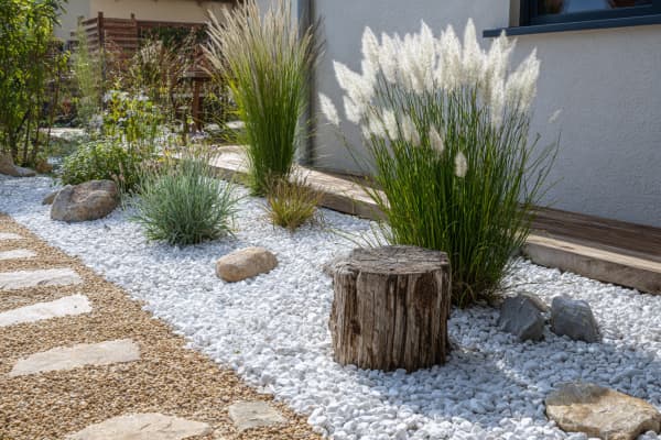 Garten mit weißem Marmorkies und Ziergräsern.