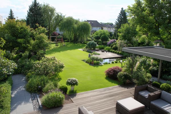 Grosser Garten mit Rasenfläche, Terrasse, Teich und Beeten.