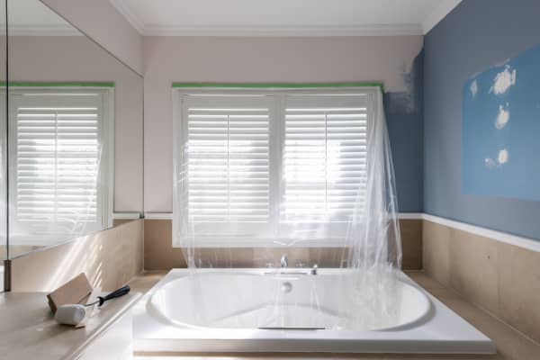 Ein Badezimmer mit abgedeckter Badewanne und teils weißer, teils blau gestrichener Wand.