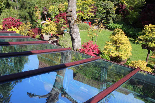 Terrassenüberdachung aus Plexiglas und weinrotem Gestell.