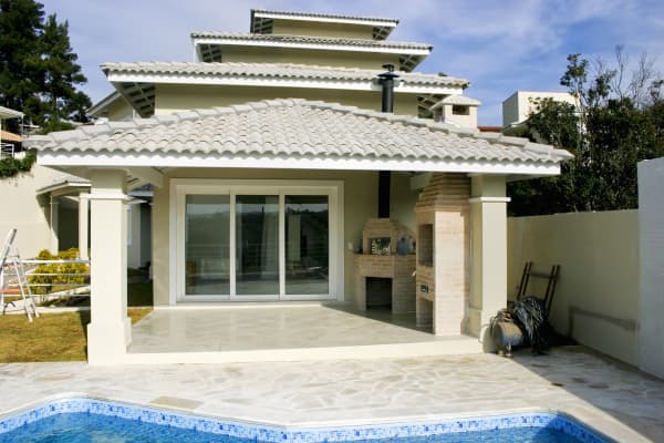 Terrassenüberdachung mit Ziegeln und Marmorboden vor einem Swimmingpool.