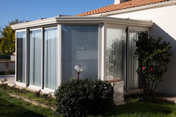 Großer Wintergarten mit weißen Vorhängen als Wohnbereich.