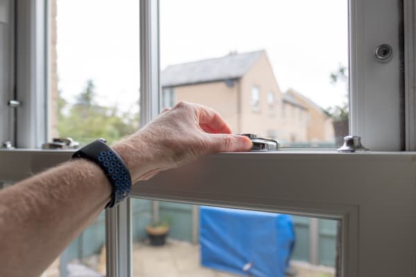 Schiebefenster wird geöffnet – Hand betätigt Fenstergriff im Haus