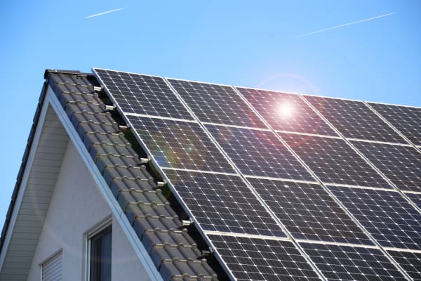 Solarmodule auf Hausdach bei blauem Himmel und Sonnenschein