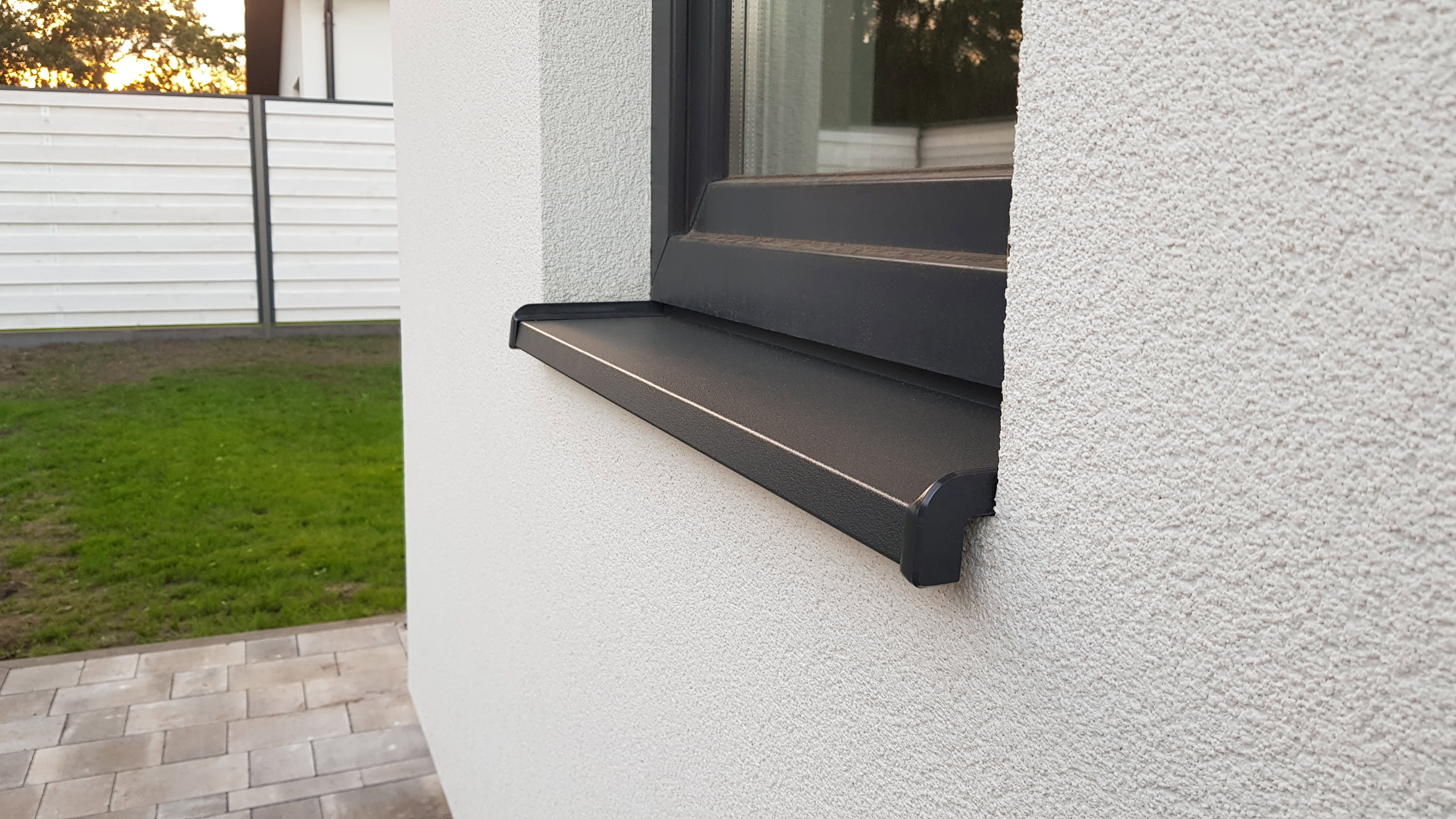 Schwarze Außenfensterbank aus Aluminium an weißer Fassade