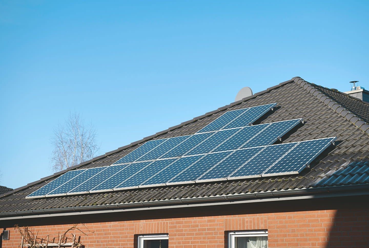 Einfamilienhaus mit großer Solaranlage auf dem Dach vor blauem Himmel