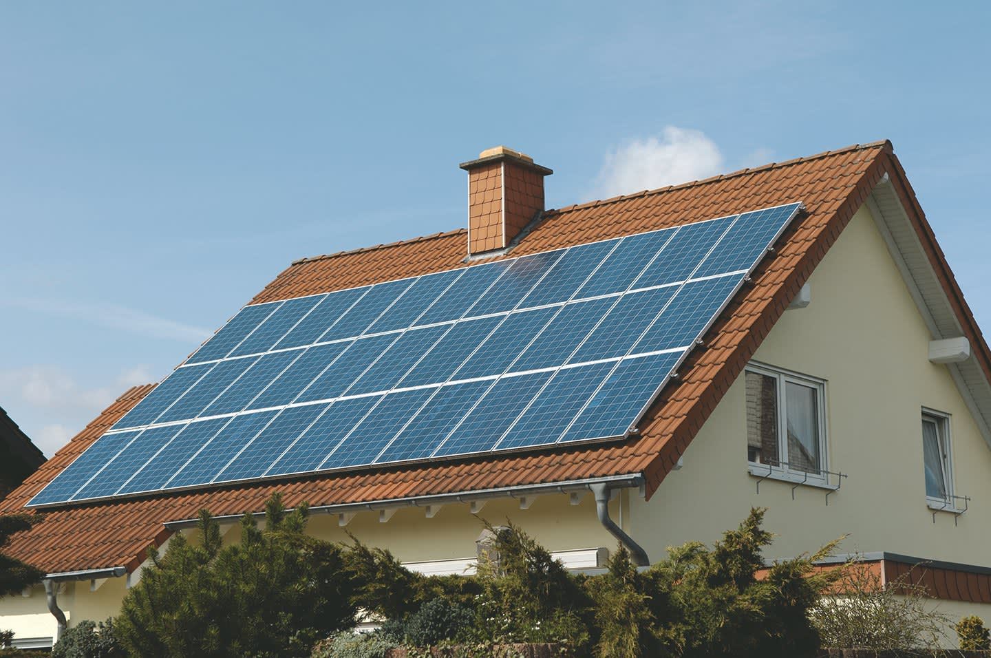 Einfamilienhaus mit großer Solaranlage auf dem Dach vor blauem Himmel