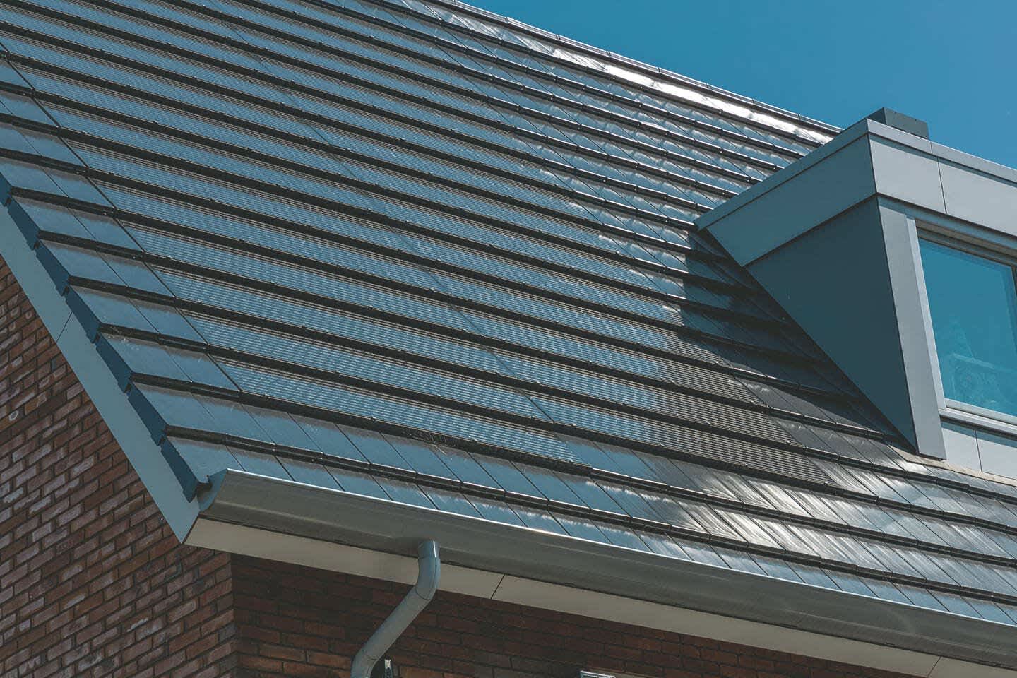 Einfamilienhaus mit großer Indach-Solaranlage auf dem Dach vor blauem Himmel