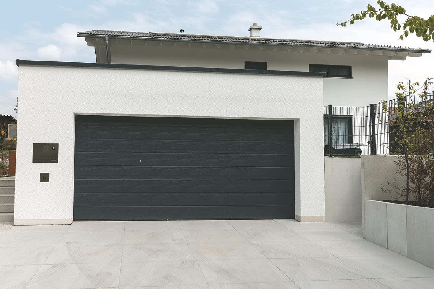 Beton Großraumgarage mit breitem Tor vor einem Wohnhaus