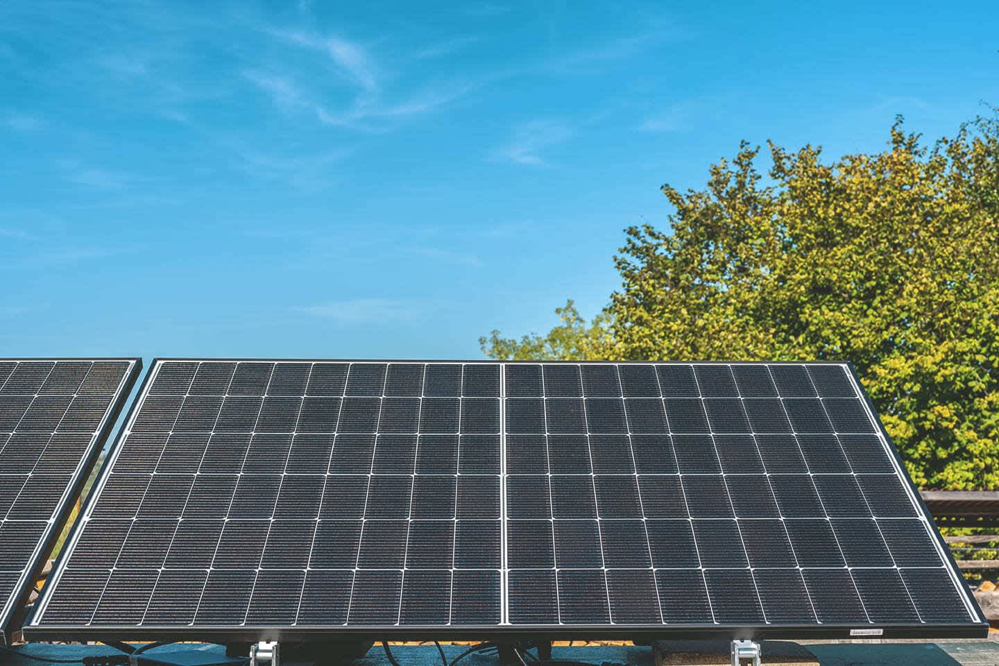 Mehrere Solarmodule aufgeständert auf einem Gebäude vor blauem Himmel.