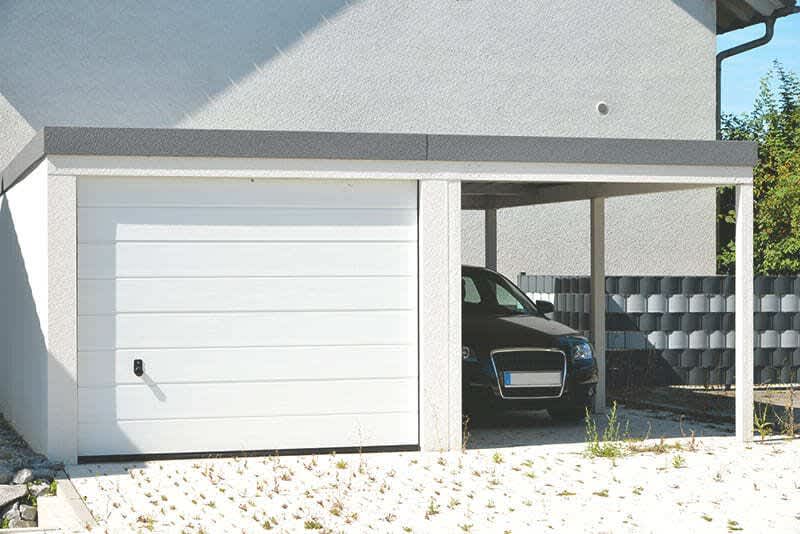 Weiße Fertiggarage mit einem Carport daneben gebaut