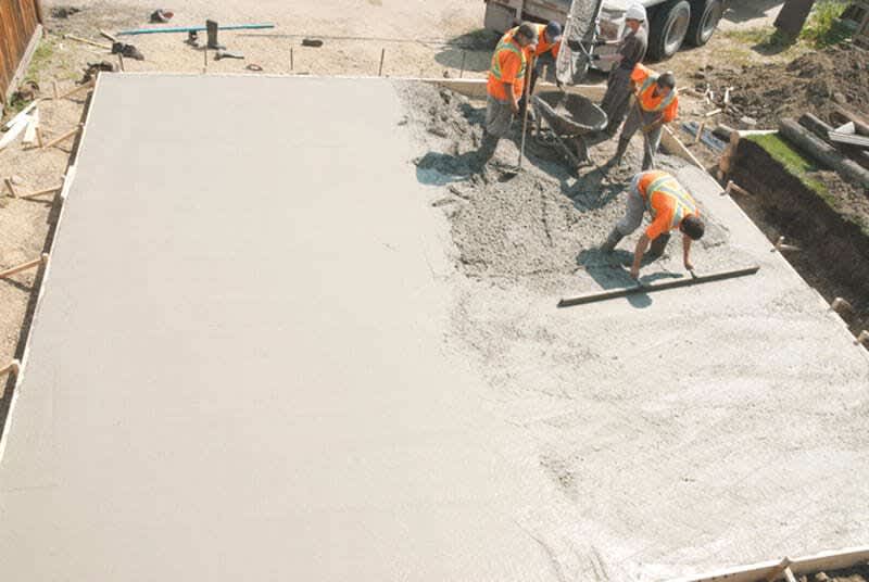 Arbeiter betonieren eine Schalung für das Garagenfundament.