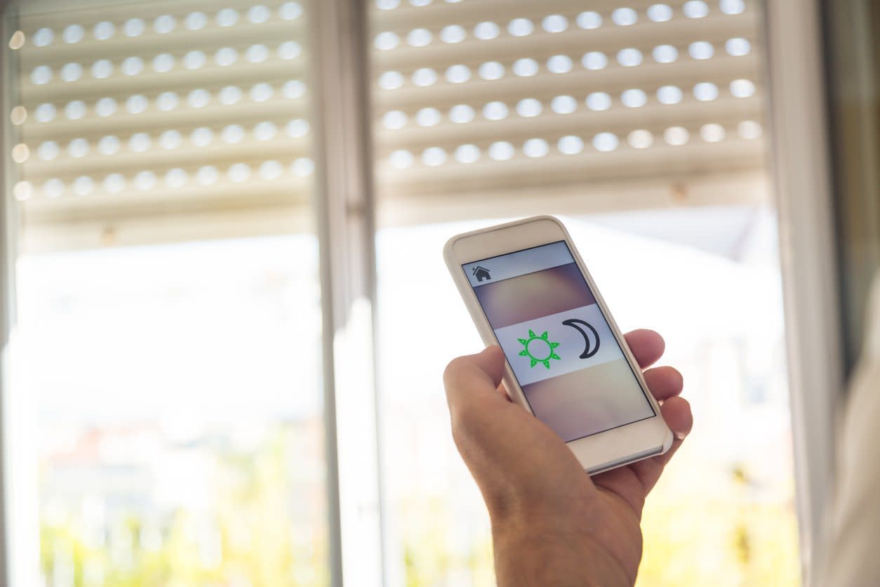 Eine Hand steuert Rollladen mithilfe einer App