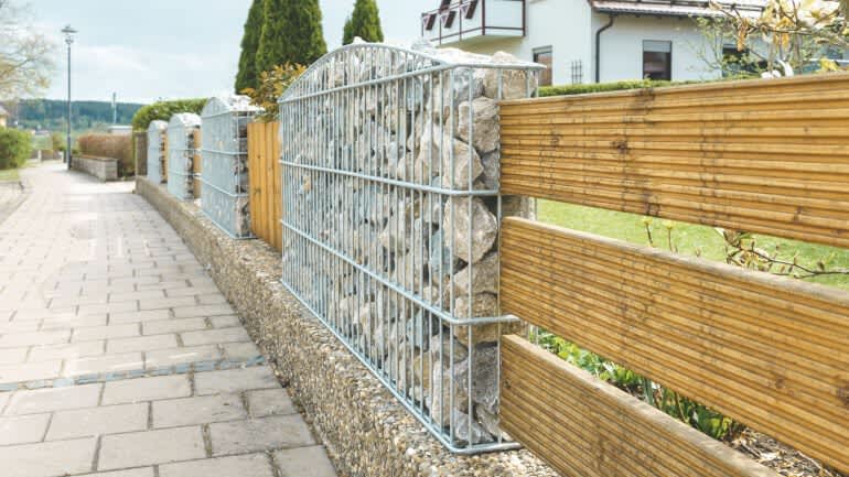 Aus Steinen und Holz bestehnender Zaun an der Straße