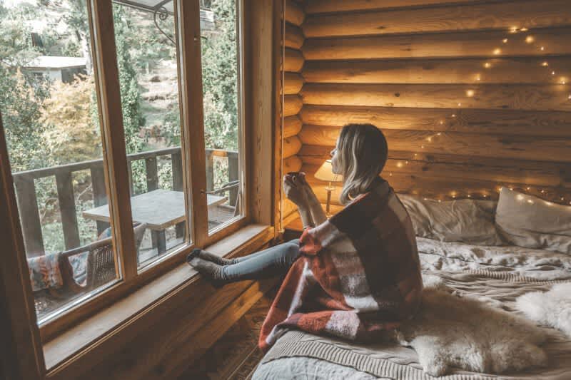 Frau sitzt auf einem bett im Holzhaus